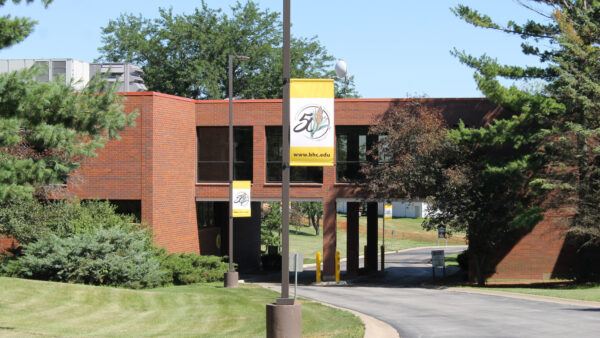 a street light with a sign on it in front of a college building